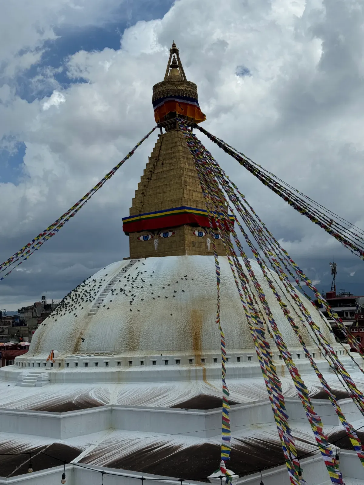 The great stupa of Boudhanath in Kathmandu, its gilded spire and Buddha eyes above the white dome, with prayer flags radiating out