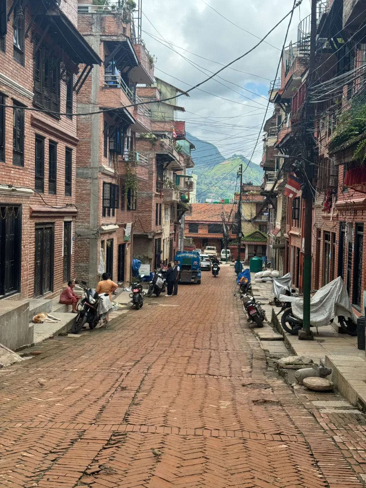 The wide brick-paved main street of Khokana, a traditional Newar village south of Patan, lined with brick houses and carved wooden windows