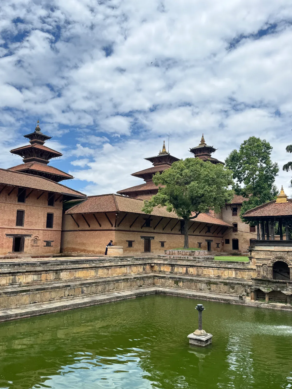 Pagoda roofs of the royal palace at Patan Durbar Square reflected in the stepped stone water tank